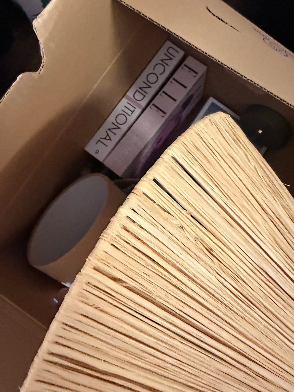 Een doos met een lampenkap en boeken, ingepakt voor een woning