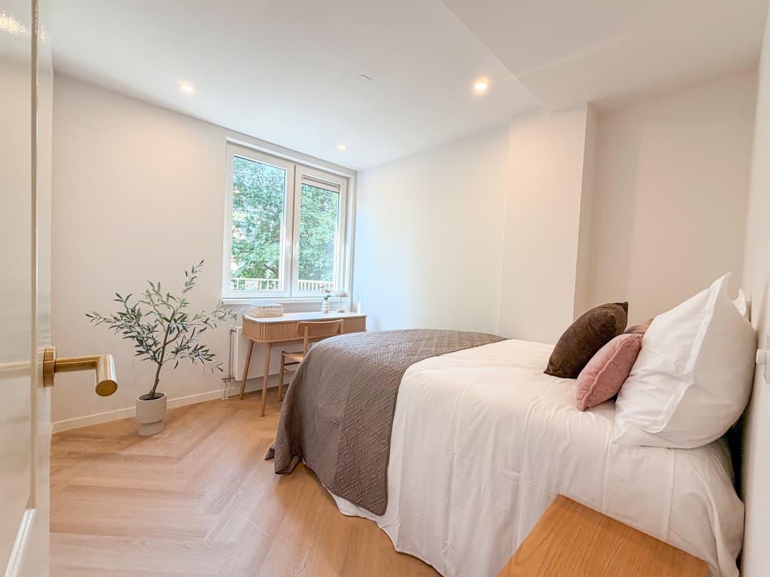 Slaapkamer in een appartement in Rotterdam, ingericht met een bed, textiel en lampen